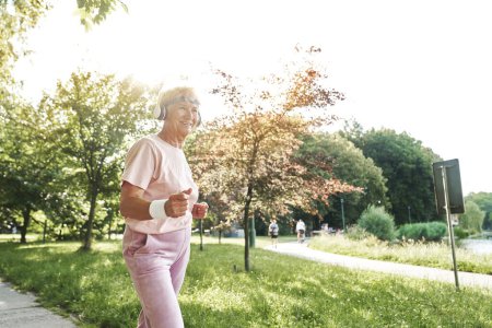 Téléchargez les photos : Femme âgée faisant de l'exercice dans le parc en été - en image libre de droit