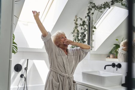 Foto de Senior mujer caucásica estiramiento en el baño en la mañana - Imagen libre de derechos