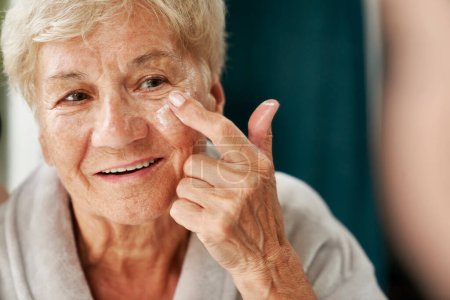 Photo for Senior woman applying a face cream - Royalty Free Image