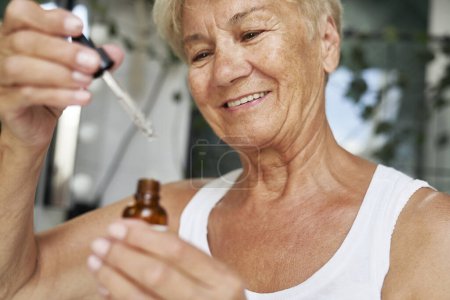Photo for Senior woman about to use the face serum - Royalty Free Image
