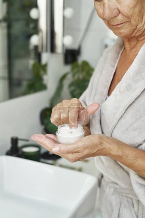 Téléchargez les photos : Femme âgée sur le point d'appliquer une crème pour le visage - en image libre de droit