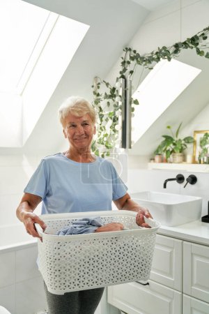 Photo for Portrait of senior caucasian woman holding a laundry basket - Royalty Free Image