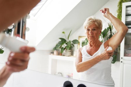 Photo for Senior caucasian woman applying antiperspirant - Royalty Free Image