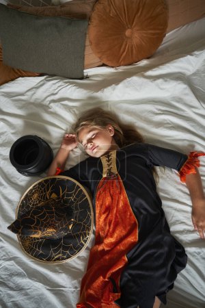 Photo for Elementary age girl  sleeping on bed wearing witch costume - Royalty Free Image