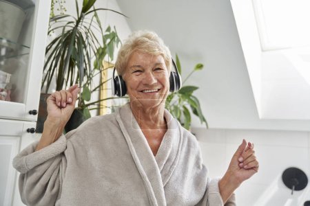 Photo for Senior caucasian woman using headphones and dancing in the bathroom - Royalty Free Image
