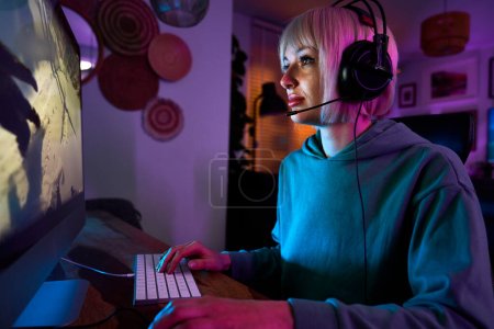 Photo for Young caucasian woman playing game at night on Desktop PC - Royalty Free Image