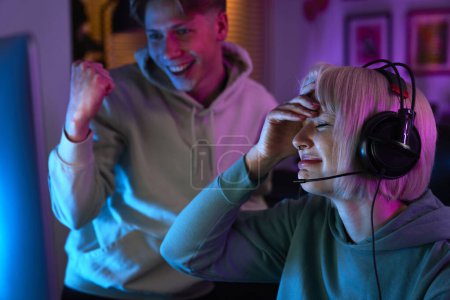 Téléchargez les photos : Femme caucasienne jouant au jeu la nuit sur PC de bureau et son ami la soutient - en image libre de droit