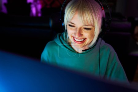 Photo for Caucasian young woman playing game at night among neon lightning - Royalty Free Image