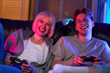 Téléchargez les photos : Couple caucasien jouer jeu vidéo avec des tampons de jeu et avoir du plaisir - en image libre de droit