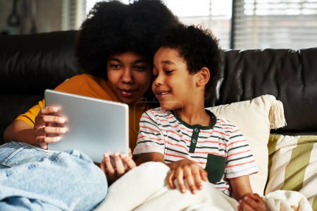 Téléchargez les photos : Deux enfants naviguant sur tablette numérique dans le salon - en image libre de droit