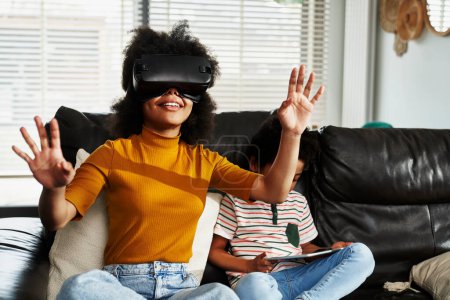Photo for Teenage girl wearing virtual reality simulator to play video game in the living room - Royalty Free Image