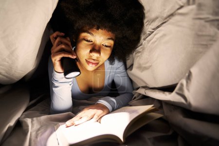 Téléchargez les photos : Adolescente naviguant tablette numérique sous couverture la nuit - en image libre de droit