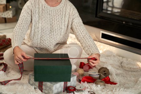 Foto de Mujer irreconocible embalaje regalos para Navidad con un lazo - Imagen libre de derechos
