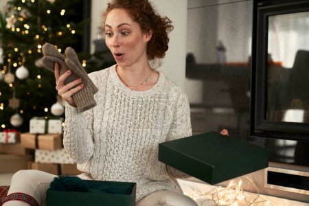 Foto de Mujer sorprendida desempacando regalos durante la Navidad - Imagen libre de derechos