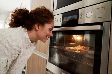 Photo for Caucasian woman baking gingerbread cookies for Christmas in the oven - Royalty Free Image