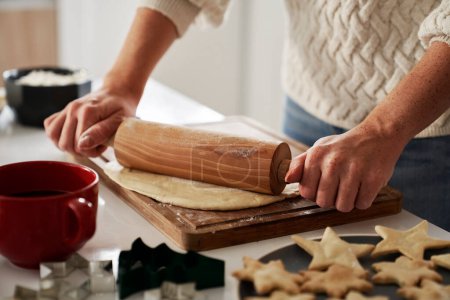 Téléchargez les photos : Femme méconnaissable utilisant rouleau à pâtisserie pour préparer la pâte pour les biscuits de Noël - en image libre de droit