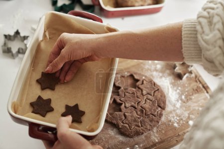Photo for Top view of woman putting gingerbread cookies on baking tray - Royalty Free Image