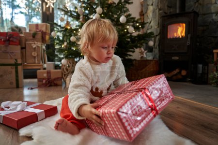 Photo for Caucasian toddler unpacking Christmas present - Royalty Free Image