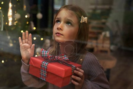 Photo for Little girl looking through the window and and looking up - Royalty Free Image
