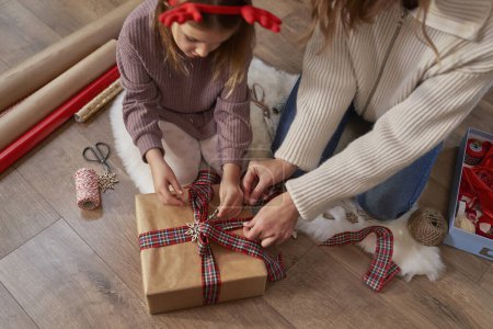 Photo for High angle view of caucasian girl and mother wrapping Christmas gifts on the floor - Royalty Free Image