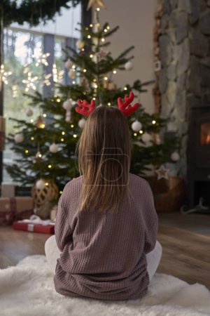 Foto de Vista trasera de la chica con astas y mirando el árbol de Navidad - Imagen libre de derechos