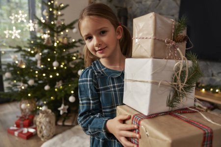 Téléchargez les photos : Élémentaire âge fille portant un tas de cadeaux de Noël - en image libre de droit