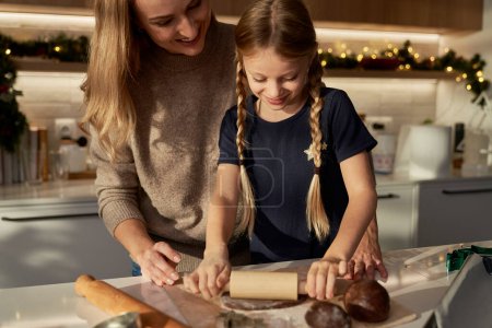 Photo for Caucasian mother and daughter making gingerbreads in domestic kitchen - Royalty Free Image