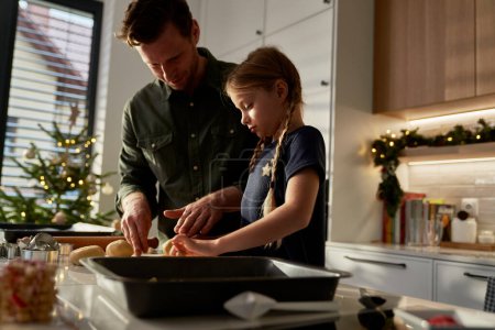 Téléchargez les photos : Père et fille caucasiens faisant des pains d'épice dans la cuisine domestique - en image libre de droit