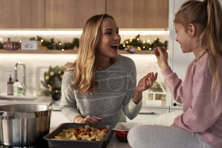Photo for Caucasian mother and daughter tasting food before Christmas - Royalty Free Image