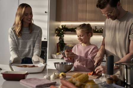 Photo for Caucasian family of three cooking before Christmas with fun - Royalty Free Image