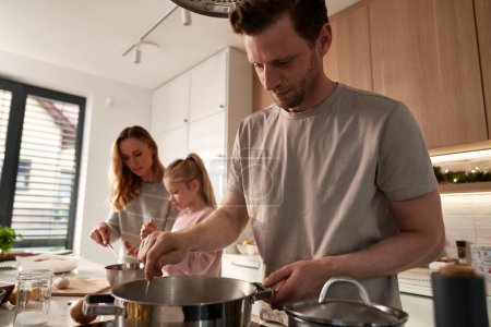 Photo for Caucasian family of three preparing food for Christmas in domestic kitchen - Royalty Free Image