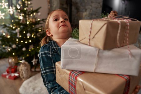 Photo for Elementary age girl barely carrying a pile of Christmas presents - Royalty Free Image