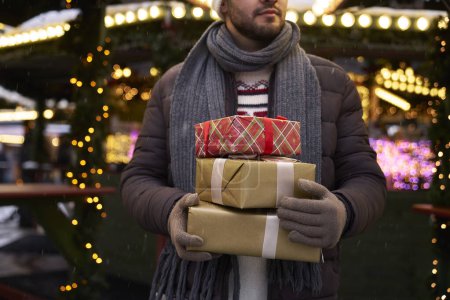 Téléchargez les photos : Homme caucasien méconnaissable portant une pile de cadeaux de Noël - en image libre de droit