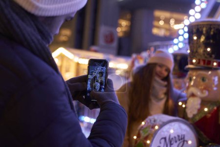 Téléchargez les photos : Homme prenant une photo de son amie pendant le marché de Noël - en image libre de droit