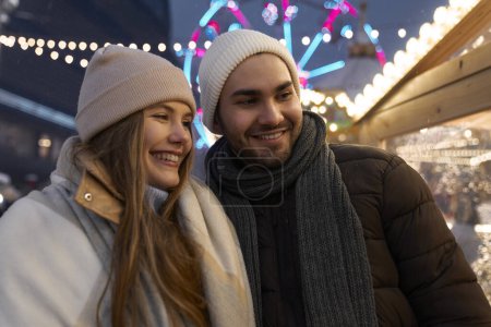 Téléchargez les photos : Couple caucasien s'amuser sur le marché de Noël la nuit - en image libre de droit