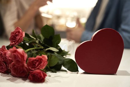 Téléchargez les photos : Boîte de chocolats et bouquet de roses quand un couple en arrière-plan - en image libre de droit