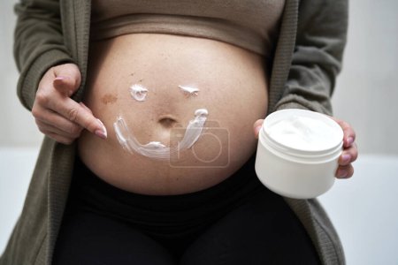 Foto de Humectante en el abdomen humano de la mujer embarazada - Imagen libre de derechos