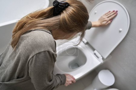 Foto de Mujer inclinándose sobre el inodoro y teniendo náuseas - Imagen libre de derechos