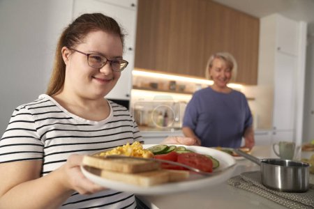 Photo for Down syndrome woman serving breakfast - Royalty Free Image