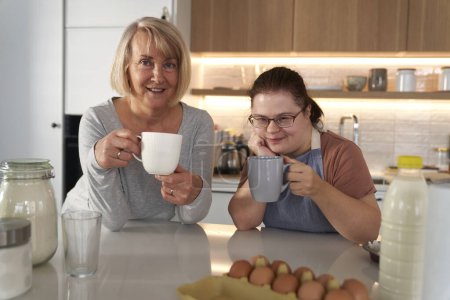 Foto de Retrato del síndrome de Down mujer y su madre en la cocina - Imagen libre de derechos