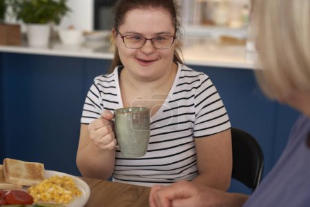Foto de Síndrome de Down mujer y su madre charlando durante el desayuno - Imagen libre de derechos