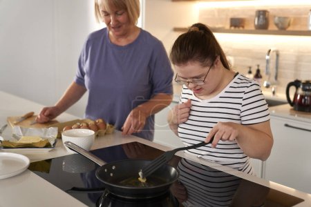 Photo for Down syndrome woman and her mother preparing breakfast together - Royalty Free Image