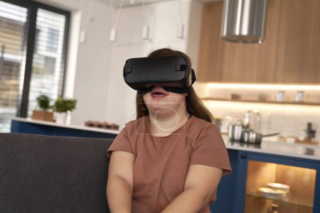 Téléchargez les photos : Down girl utilisant un appareil de réalité virtuelle à la maison - en image libre de droit