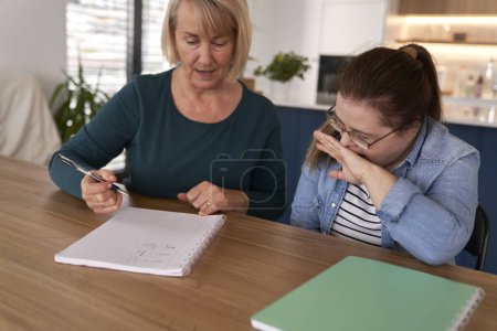 Foto de Síndrome de Down estudiando en casa con la ayuda de su madre - Imagen libre de derechos