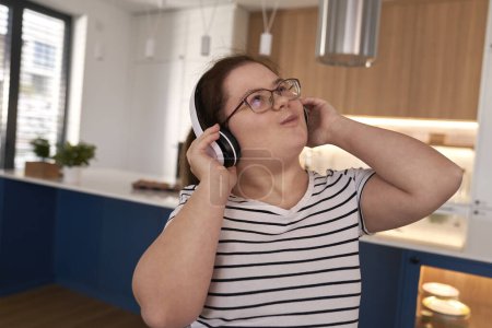 Photo for Close up of down syndrome woman using headphones and dancing in the living room - Royalty Free Image