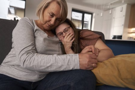 Foto de Síndrome de Down mujer acostada en el sofá y hablando con su madre - Imagen libre de derechos