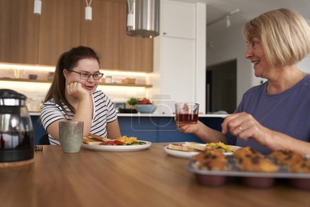 Foto de Síndrome de Down mujer y su madre charlando durante el desayuno - Imagen libre de derechos