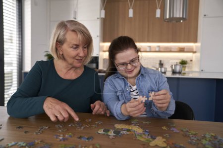 Téléchargez les photos : Focus down syndrome femme et sa mère assembler des puzzles à la maison - en image libre de droit
