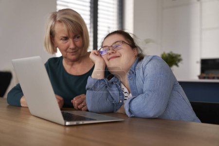 Téléchargez les photos : Femme trisomique utilisant l'ordinateur avec l'aide de sa mère - en image libre de droit
