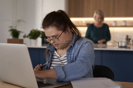 Téléchargez les photos : Le syndrome de Down étudie sur ordinateur à la maison - en image libre de droit